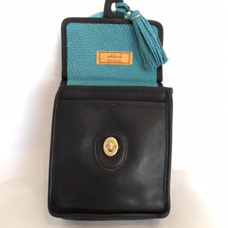 Formerly serious black Coach mailbag style purse becomes charming and witty with its exuberant teal handle and tassel. In the same contrasting color inside, the lining of genuine goat-skin is soft and supple as the gorgeous leather outside.