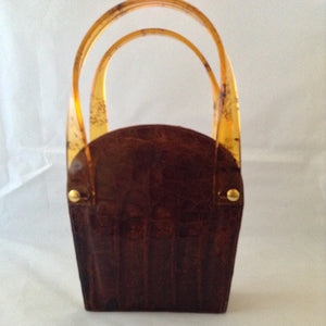 Vintage 1960s brown crocodile purse with lovely lucite handles. This unusual shape will stand out in a crowd. Hidden chain, if you love a shoulder bag.