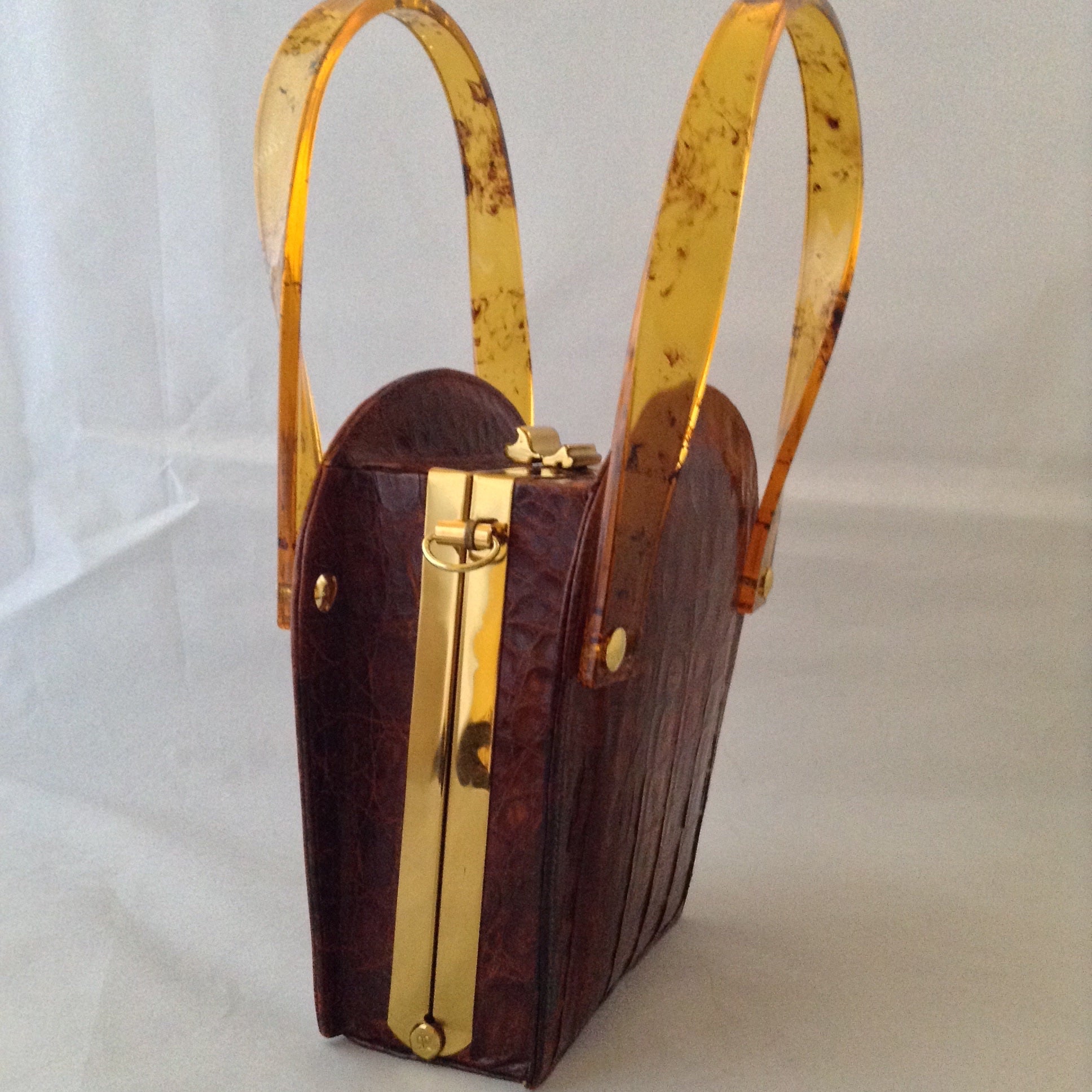 Vintage 1960s brown crocodile purse with lovely lucite handles. This unusual shape will stand out in a crowd. Hidden chain, if you love a shoulder bag.