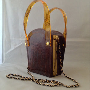 Vintage 1960s brown crocodile purse with lovely lucite handles. This unusual shape will stand out in a crowd. Hidden chain, if you love a shoulder bag.