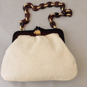 Vintage purse with supple vanilla leather which complements the bold browns and golds of the strolling elephants adorning it. A tortoise and golden chain handle and lucite frame are so classic, creamy and dreamy.   Dimensions - 6" Height; 8" Width; 15" Length with chain