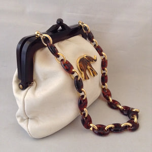 Vintage purse with supple vanilla leather which complements the bold browns and golds of the strolling elephants adorning it. A tortoise and golden chain handle and lucite frame are so classic, creamy and dreamy.   Dimensions - 6" Height; 8" Width; 15" Length with chain
