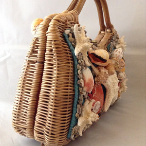 Lovely tan straw-grass purse made in Bali in the 1960s imagines a tropical sea bed with red silk lining. 1,014 shells, large and small, went into the making of this stunning piece. (Wanna count 'em?)  Dimensions - 8-1/2" Height; 13-1/2" Width"; 11 Length