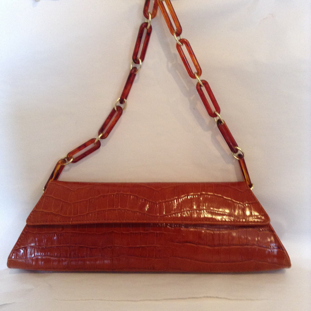 Burnt ochre trapezoid shaped purse with a vintage tortoise chain handle that fits neatly inside in case if you want to carry it as a clutch.  The striking burnt ocher color makes this the perfect fall to winter handbag.