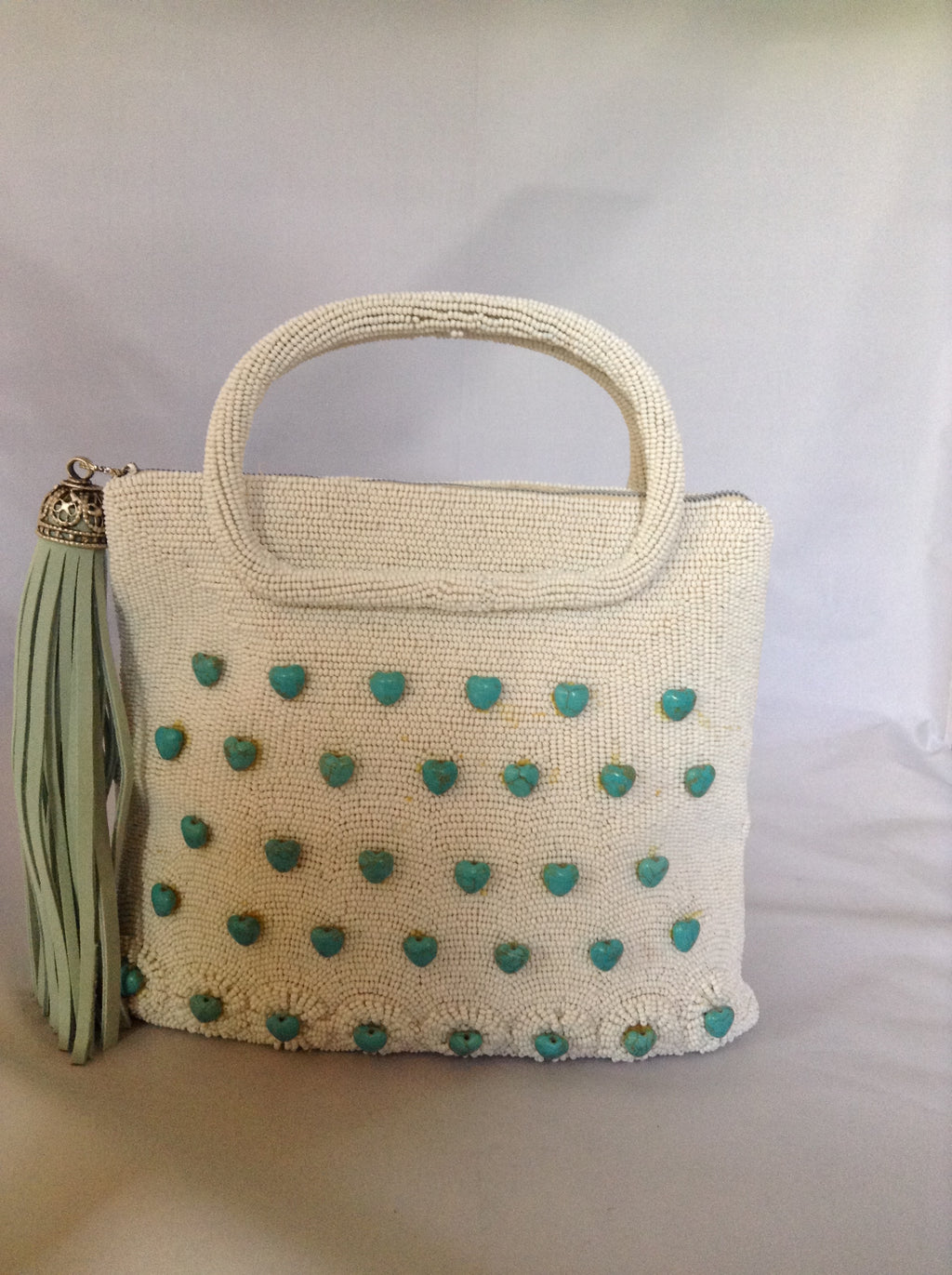 42 genuine turquoise hearts adorn this 1950's vintage white beaded purse from Paris. With its original silk lining and aqua suede tassel you'll channel Audrey wherever you go.  Dimensions - 7.5"Height; 8" Width; 3" Depth; Handle 3"