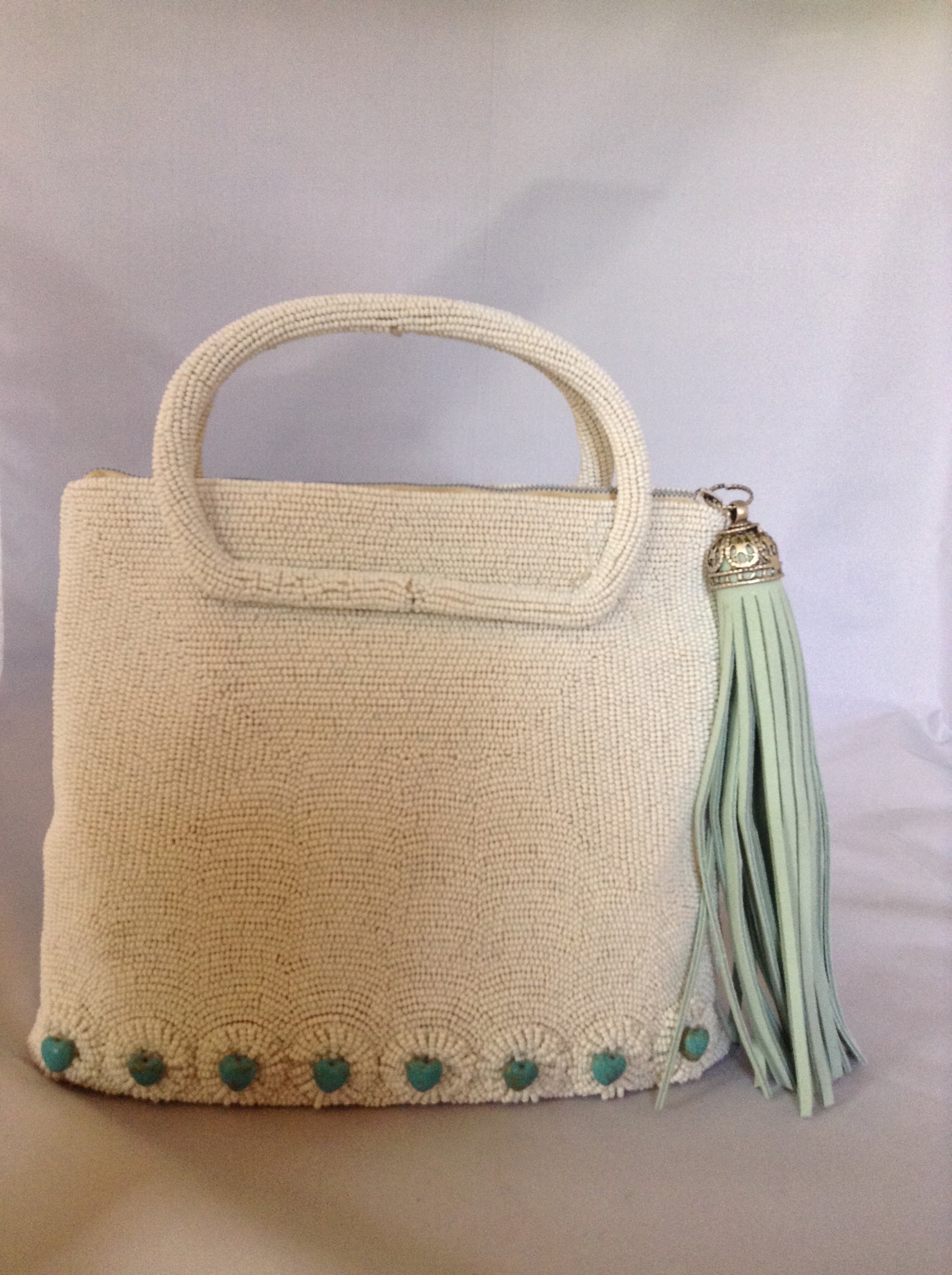 42 genuine turquoise hearts adorn this 1950's vintage white beaded purse from Paris. With its original silk lining and aqua suede tassel you'll channel Audrey wherever you go.  Dimensions - 7.5"Height; 8" Width; 3" Depth; Handle 3"