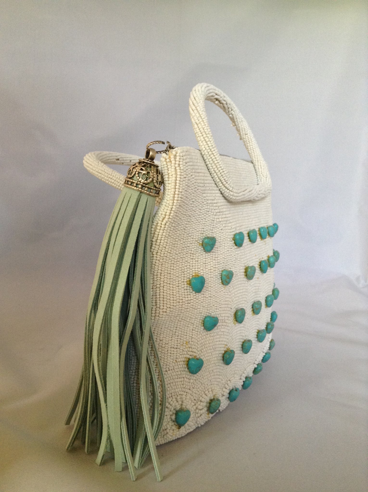 42 genuine turquoise hearts adorn this 1950's vintage white beaded purse from Paris. With its original silk lining and aqua suede tassel you'll channel Audrey wherever you go.  Dimensions - 7.5"Height; 8" Width; 3" Depth; Handle 3"