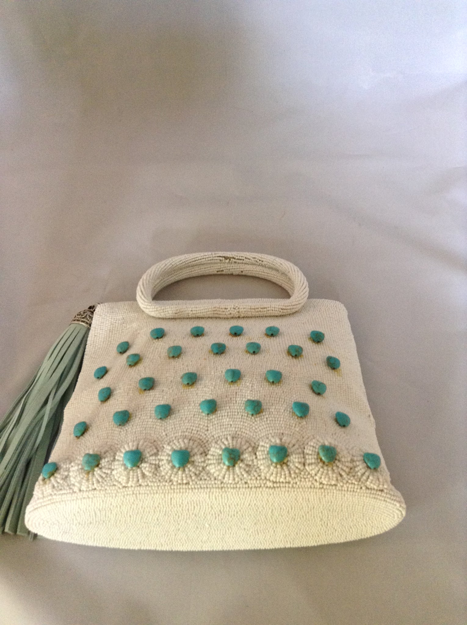 42 genuine turquoise hearts adorn this 1950's vintage white beaded purse from Paris. With its original silk lining and aqua suede tassel you'll channel Audrey wherever you go.  Dimensions - 7.5"Height; 8" Width; 3" Depth; Handle 3"