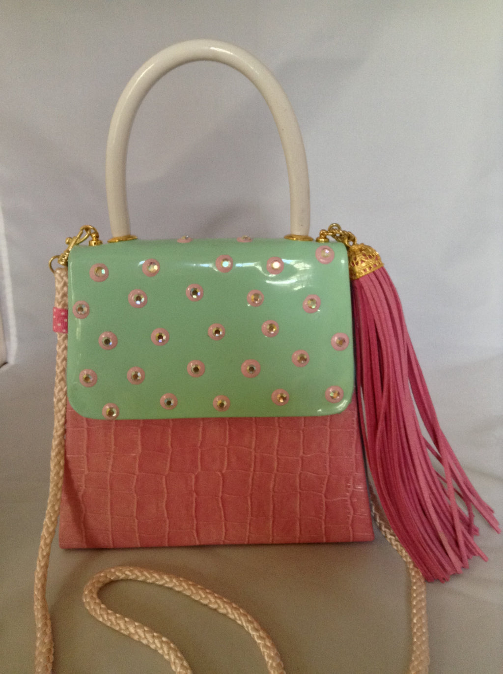 Faux croc in pink and sea-foam patent leather adorned with crystal beads and a pink suede tassel, this 60's bag has a new life with its striped silk lining and detachable cross-body cord.  Dimensions - 7" Height; 7.5" Width; 3" Depth; Handle 4"; Cord 22"