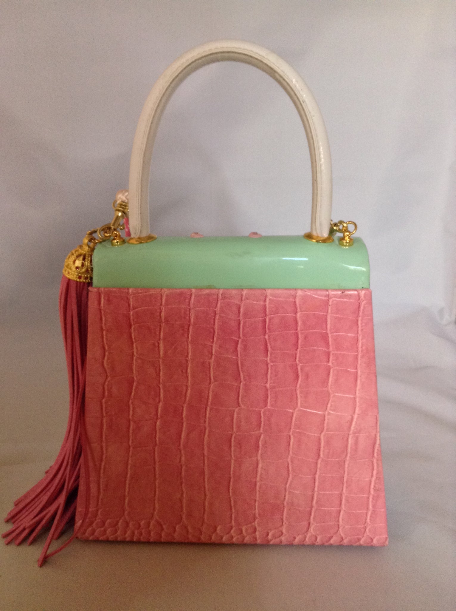 Faux croc in pink and sea-foam patent leather adorned with crystal beads and a pink suede tassel, this 60's bag has a new life with its striped silk lining and detachable cross-body cord.  Dimensions - 7" Height; 7.5" Width; 3" Depth; Handle 4"; Cord 22"