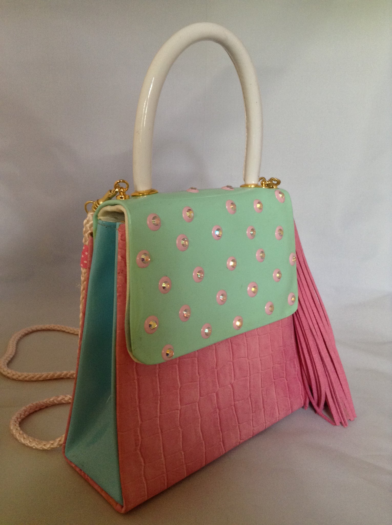 Faux croc in pink and sea-foam patent leather adorned with crystal beads and a pink suede tassel, this 60's bag has a new life with its striped silk lining and detachable cross-body cord.  Dimensions - 7" Height; 7.5" Width; 3" Depth; Handle 4"; Cord 22"