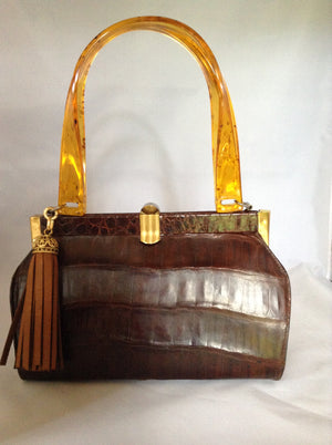 Vintage brown alligator purse with amber lucite handles, original hardware, soft leather lining and an amber tassel combine to make this classic Spanish beauty your go-to purse forever.  Dimensions - Height 6.5"; Width 9"; Depth 4"; Handle 7"