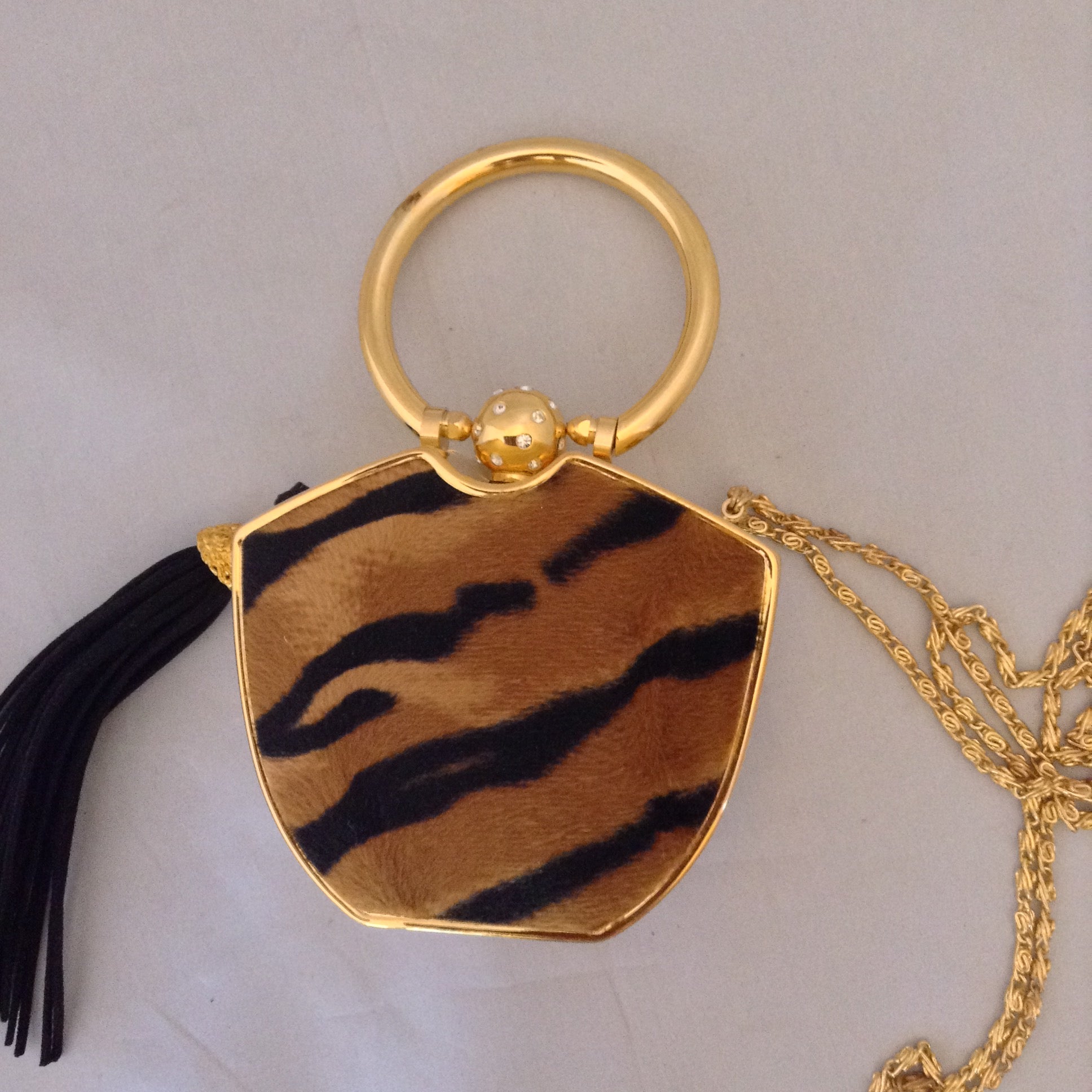 Darling yet daring, this vintage solid brass box purse roars attitude! Plush faux tiger pelt, golden tiger pendant, long black tassel, hideaway shoulder chain make it a conversation piece-de-resistance!