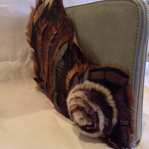 Iridescent turkey feathers and a mink pom-pom adorn this luscious teal vegan vintage leather clutch. With its inside zipper pocket & handy leather wrist strap it will even hold your notebook computer.  Dimensions - Height 9"; Width 11"; Depth 1" 