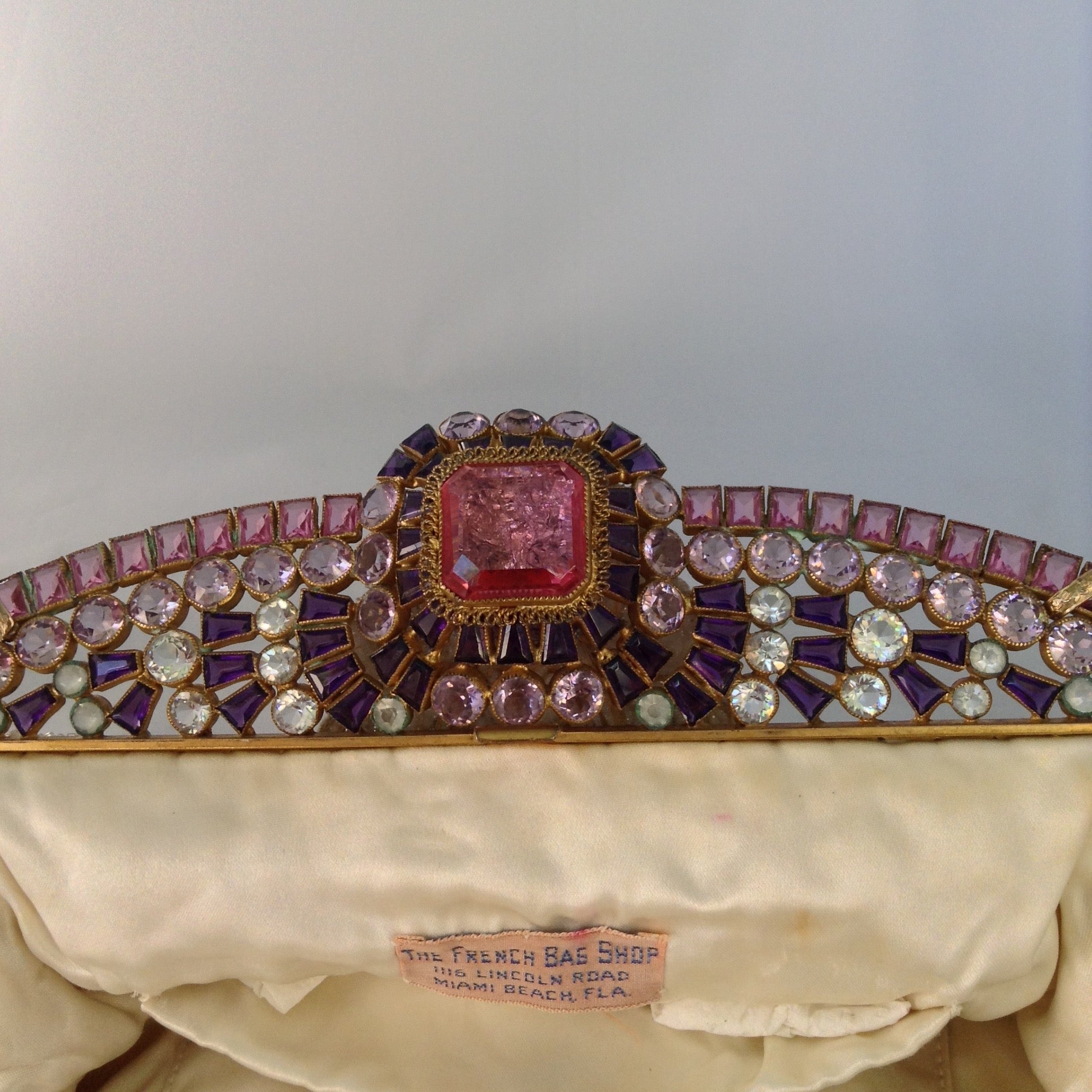 Vintage original cream beaded purse with a crown-like-handle adorned with pink, purple & white jewels, silk lining and a golden cross-body removable chain so you can gracefully toss those beads from your MardiGras float! Ooh-la-la! Magnificent, My Dear!  Dimensions - Height 6.5"; Length 9.5"; Depth 2"