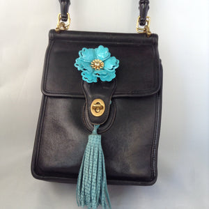 Formerly a staid and serious Coach mailbag, this supple black glove leather vintage purse becomes witty and charming with its enamel flower and new teal suede tassel and lining.  Dimensions - Height 9"; Width 7"; Depth 3"