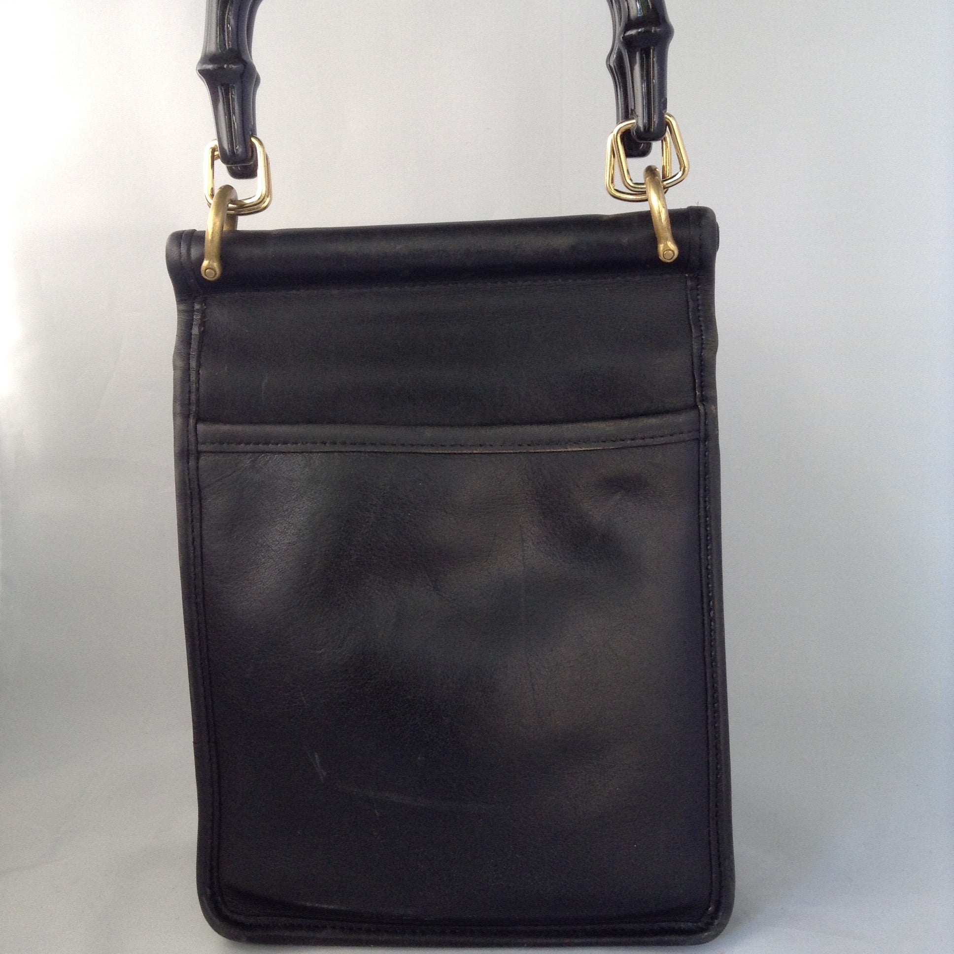Formerly a staid and serious Coach mailbag, this supple black glove leather vintage purse becomes witty and charming with its enamel flower and new teal suede tassel and lining.  Dimensions - Height 9"; Width 7"; Depth 3"