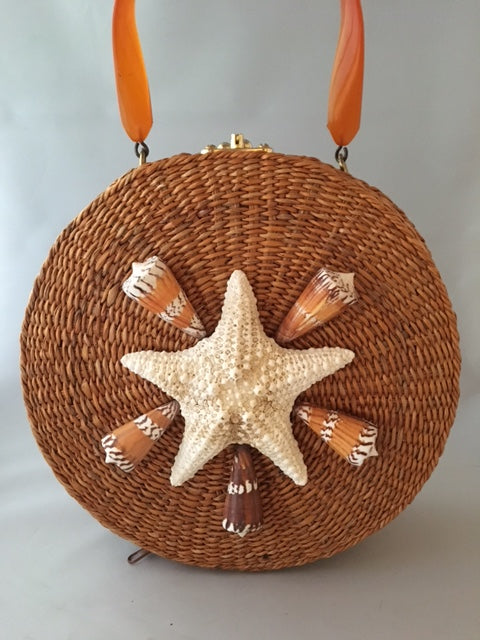 A great horned starfish and other wanna-bees encircle this unusual vintage straw bag. Leather lined with vintage lucite handle.You'll be in the inner circle wherever you take this!  Dimensions - Diameter 10"; Depth 4"; Handle 4"