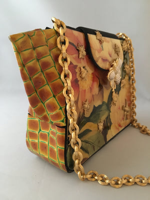 Giraffe and geraniums combine together so well in this art-deco vintage style purse from the 1970s. The vintage golden chain adds to its charm. We especially love how the giraffe print leather forms its unusually prominent gussets.   Dimensions - Height 8"; Width 9"; Depth 4"; Handle 14"