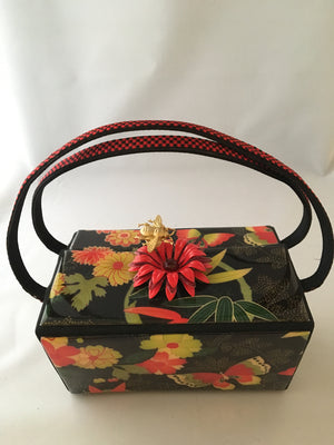 Vintage box purse with flowers and butterflies. From its cheeky checkerboard handle to its vintage enamel daisy with bouncy pouncy bee, this brilliant handbag will take you from spring through fall. Included are a matching purse for your little girl and her dolly, too!  Dimensions - Height 4.5"; Width 7"; Depth 4.5"; Handle 6"