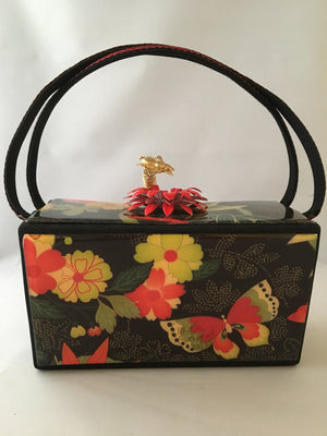 Vintage box purse with flowers and butterflies. From its cheeky checkerboard handle to its vintage enamel daisy with bouncy pouncy bee, this brilliant handbag will take you from spring through fall. Included are a matching purse for your little girl and her dolly, too!  Dimensions - Height 4.5"; Width 7"; Depth 4.5"; Handle 6"
