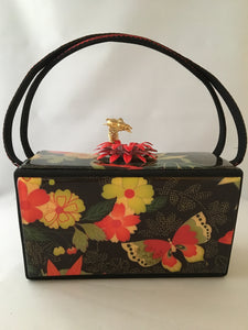 Vintage box purse with flowers and butterflies. From its cheeky checkerboard handle to its vintage enamel daisy with bouncy pouncy bee, this brilliant handbag will take you from spring through fall. Included are a matching purse for your little girl and her dolly, too!  Dimensions - Height 4.5"; Width 7"; Depth 4.5"; Handle 6"