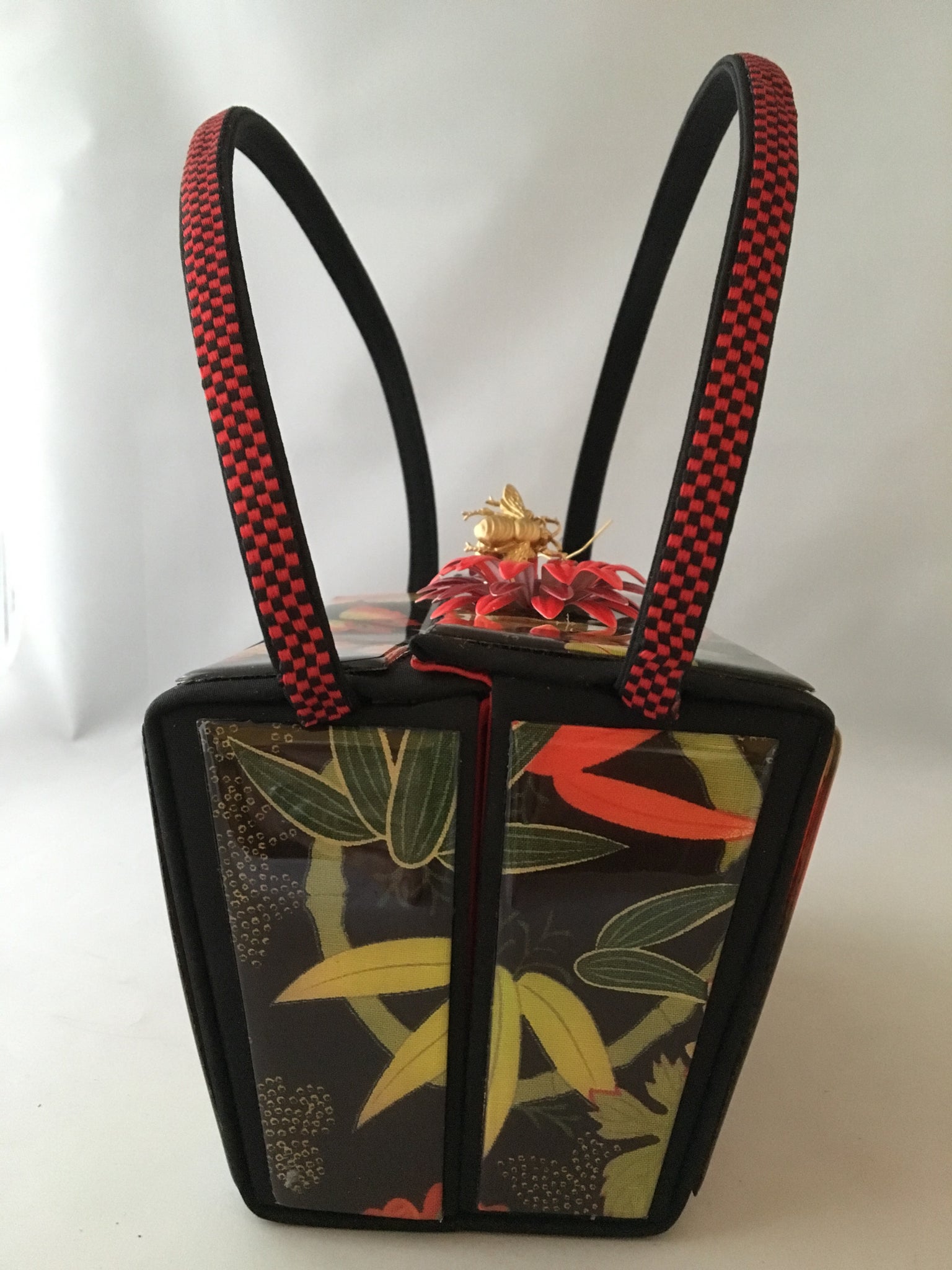 Vintage box purse with flowers and butterflies. From its cheeky checkerboard handle to its vintage enamel daisy with bouncy pouncy bee, this brilliant handbag will take you from spring through fall. Included are a matching purse for your little girl and her dolly, too!  Dimensions - Height 4.5"; Width 7"; Depth 4.5"; Handle 6"