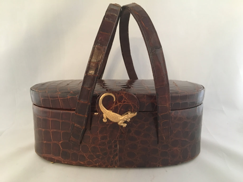 Vintage lustrous brown alligator purse with a rare oval shape with double handle, leather-lined, original mirror in the top.  Dimensions - Height 9-1/2"; Length 4"; Width 4-1/2"