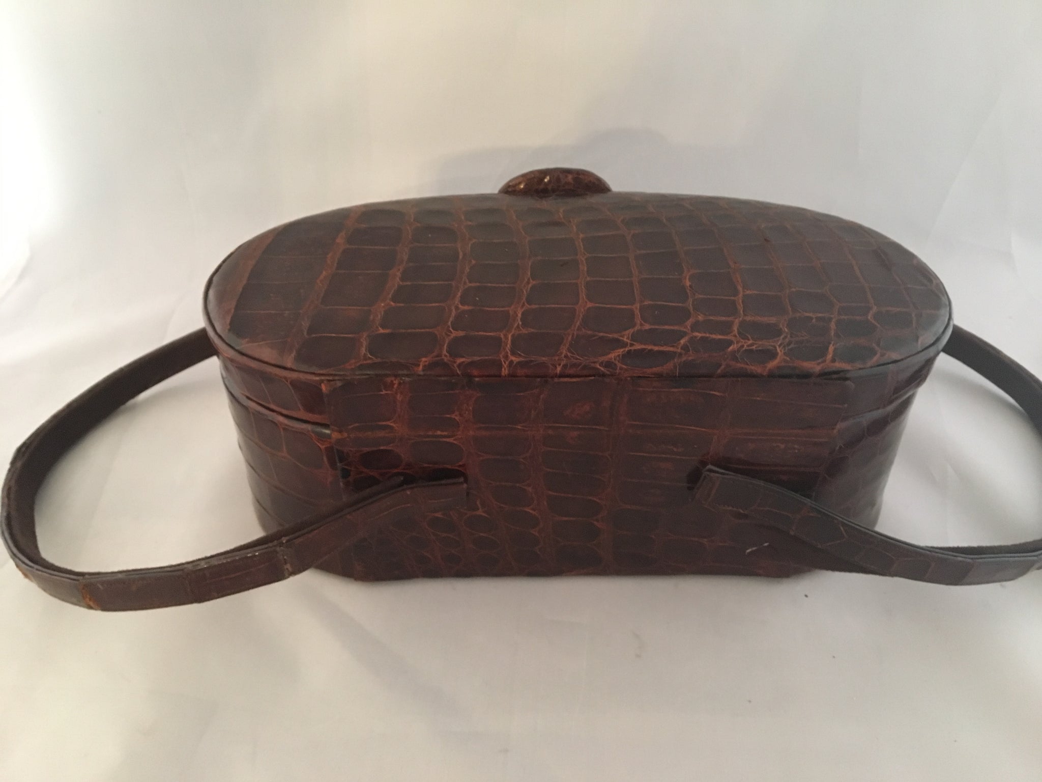 Vintage lustrous brown alligator purse with a rare oval shape with double handle, leather-lined, original mirror in the top.  Dimensions - Height 9-1/2"; Length 4"; Width 4-1/2"
