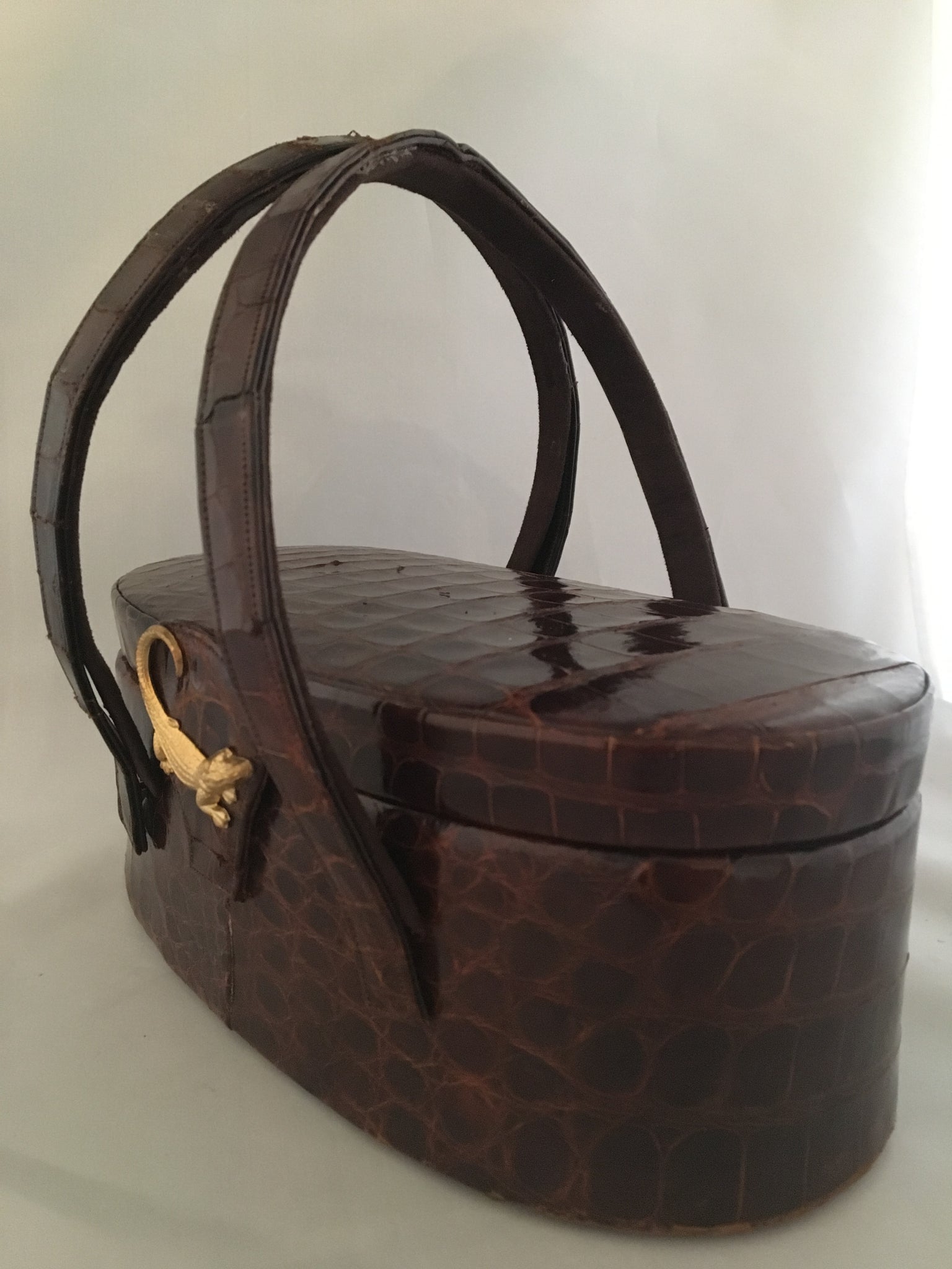 Vintage lustrous brown alligator purse with a rare oval shape with double handle, leather-lined, original mirror in the top.  Dimensions - Height 9-1/2"; Length 4"; Width 4-1/2"
