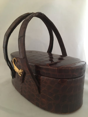 Vintage lustrous brown alligator purse with a rare oval shape with double handle, leather-lined, original mirror in the top.  Dimensions - Height 9-1/2"; Length 4"; Width 4-1/2"