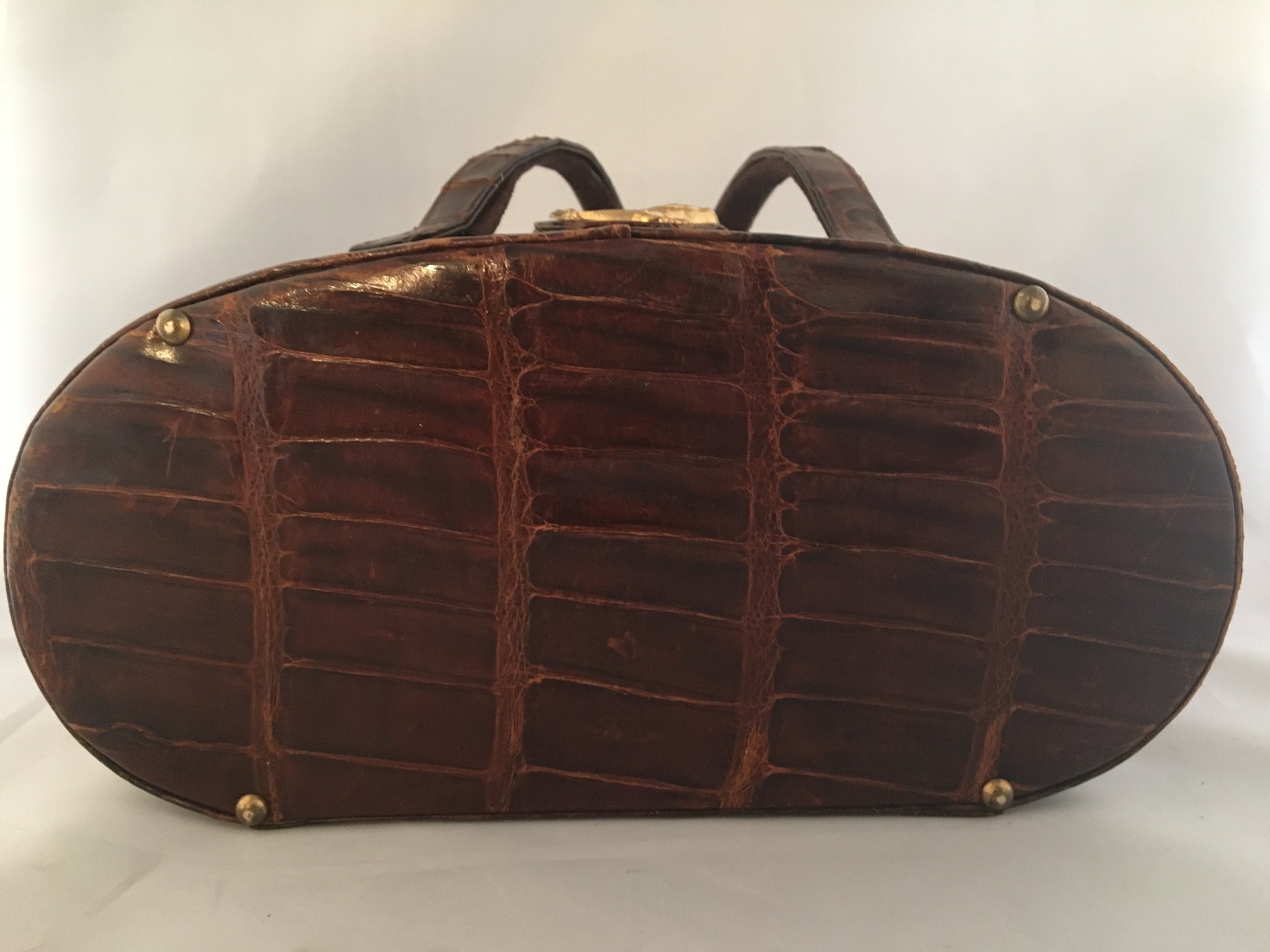 Vintage lustrous brown alligator purse with a rare oval shape with double handle, leather-lined, original mirror in the top.  Dimensions - Height 9-1/2"; Length 4"; Width 4-1/2"