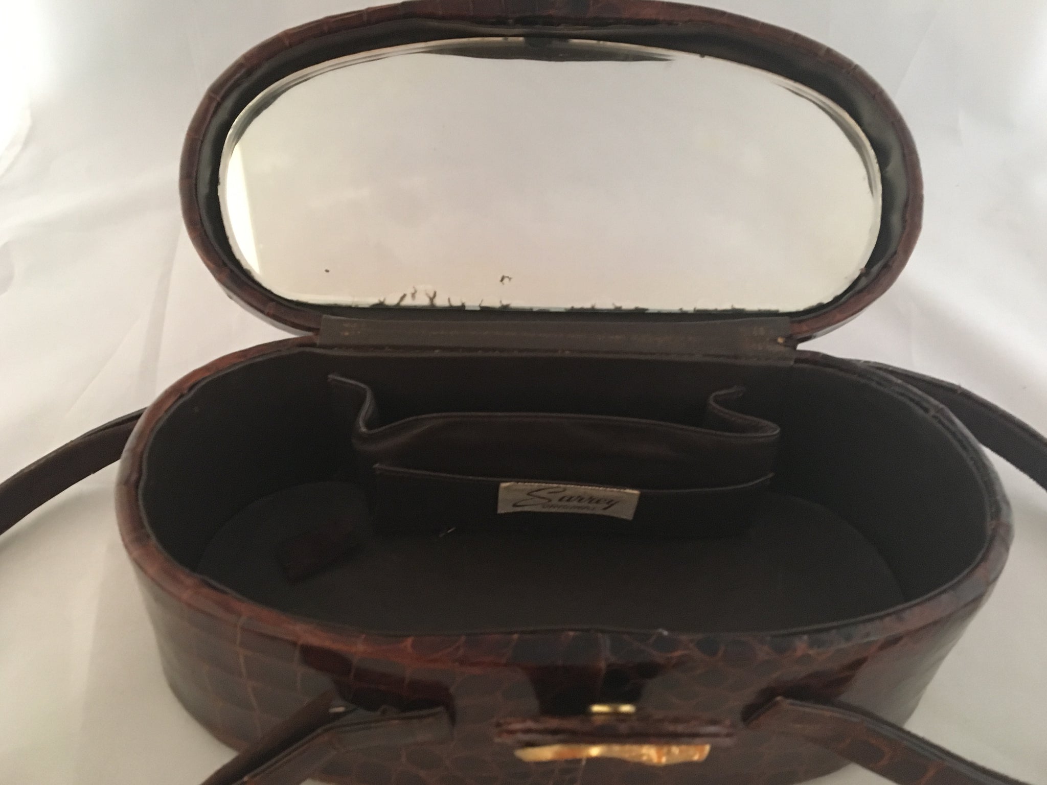 Vintage lustrous brown alligator purse with a rare oval shape with double handle, leather-lined, original mirror in the top.  Dimensions - Height 9-1/2"; Length 4"; Width 4-1/2"