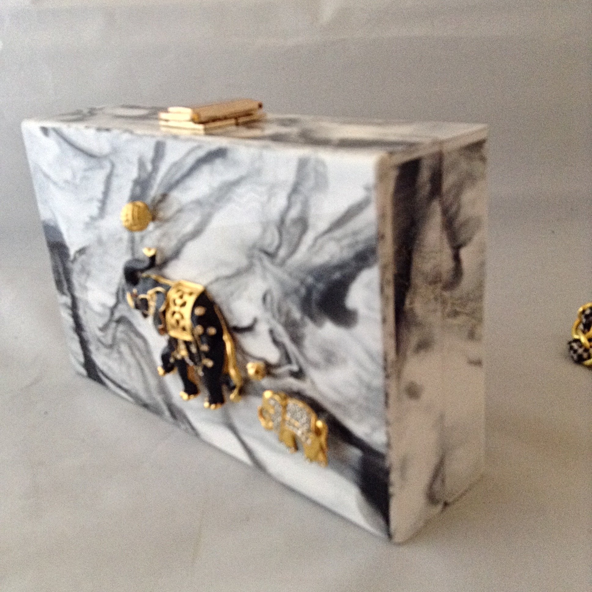 A fabulous box clutch or cross body bag with mama and baby enamel elephants, perfect for lunch to evening - or to a political rally! The hidden chain adds a whimsical touch of fun!